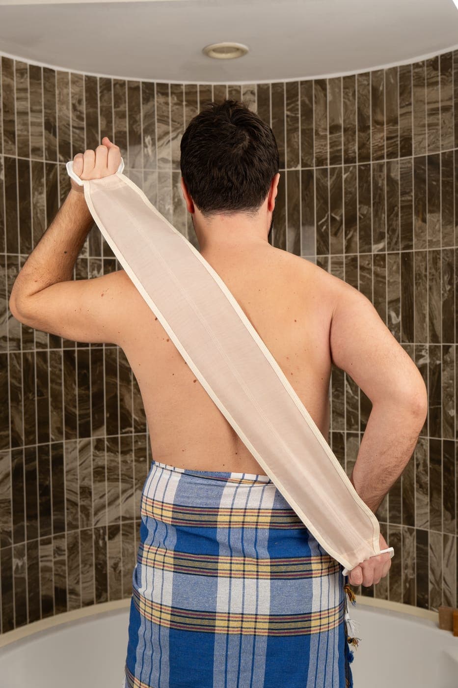 Natural raw silk back scrubber strap gliding across a bare back to smooth and polish the skin